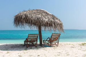 2 beach chairs in under a natural umbrella made of coconut palm leaves at an island in Lakshadweep